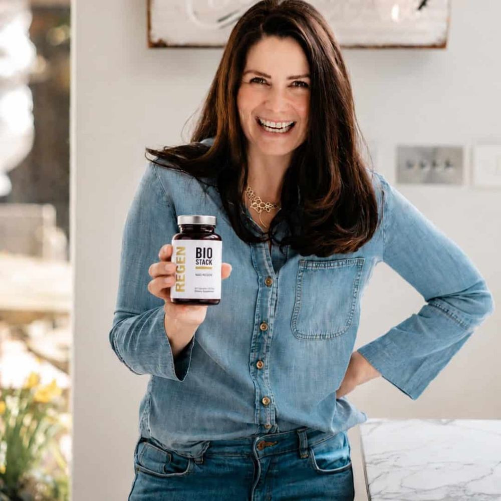 A person holding a bottle of NAD Regen in their kitchen